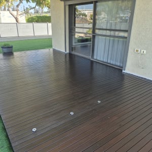 דק עץ חום ליד בית עם דשא ועציצים