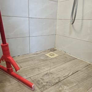 רצפת מקלחת עם מרצפות וכלי ניקוי אדום