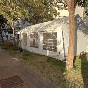 אוהל לבן גדול מוצב על דשא ליד עצים