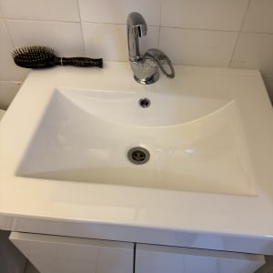 כיור לבן עם ברז מתכת מבריק ומברשת שיער