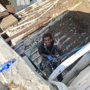 אדם עם ציוד בטיחות על גג עם עלים יבשים