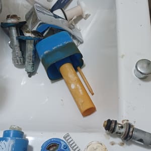 חלקי ברזים ומנגנון ניאגרה שהוחלפו מונחים בתוך כיור