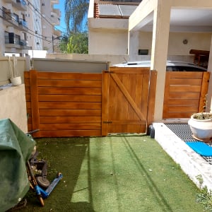 שער עץ חום בגינה עם דשא סינתטי