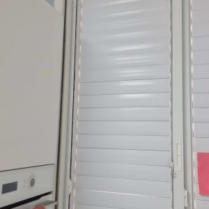 תריסים לבנים ליד חלון עם מגבת תלויה