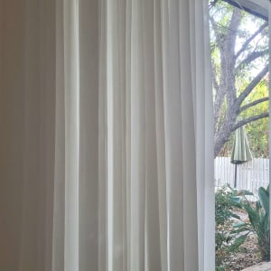 וילון לבן תלוי ליד חלון זכוכית