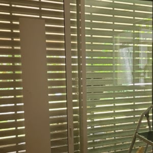 תריסים לבנים על חלון זכוכית עם מסגרת מתכת