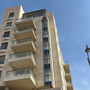 אדם תלוי על חבלים מנקה חלונות בבניין גבוה