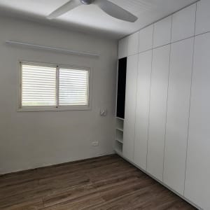 חדר עם ארון קיר לבן ורצפת עץ