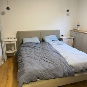 חדר שינה מסודר עם מיטה זוגית ומצעים אפורים