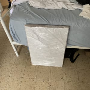 לוח עטוף בניילון מונח על הרצפה ליד מיטה