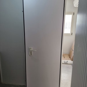 דלת לבנה עם ידית כסופה במסגרת שחורה