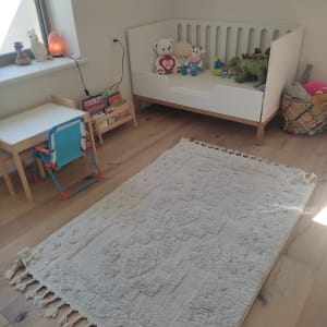 חדר ילדים עם מיטת תינוק, שטיח וצעצועים.