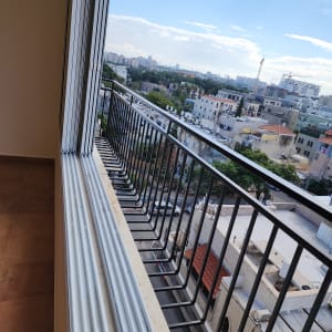 מסגרת חלון עם תריסים פתוחים ונוף עירוני