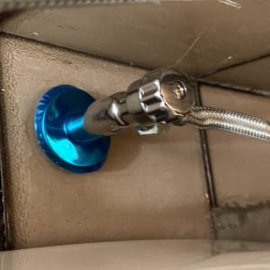 שסתום מתכת עם צינור גמיש על קיר אריחים