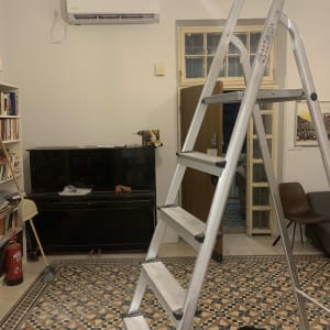 מזגן מותקן על קיר עם סולם וכלי עבודה