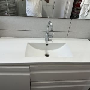 כיור אמבטיה עם ברז מותקן על ארון לבן