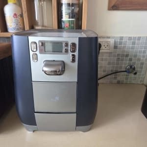 מכונת מים על משטח מטבח עם מדפים מאחוריה