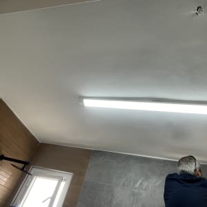 אדם צובע תקרה בחדר עם תאורה פלורסנטית