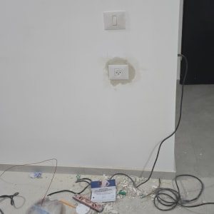 שקע חשמל בקיר עם חוטים וכלים על הרצפה