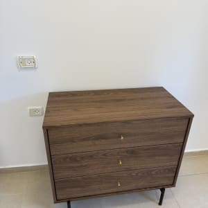 שידה מעץ עם שלוש מגירות ופטיש על הרצפה