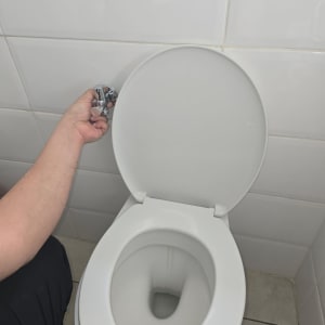 יד מחזיקה ברז ליד אסלה פתוחה