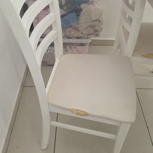 כיסא לבן עם מושב פגום ליד קופסאות פלסטיק