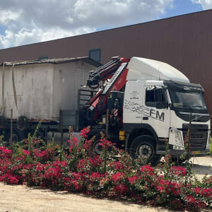 מנוף על משאית לבנה מעמיס מבנה גדול