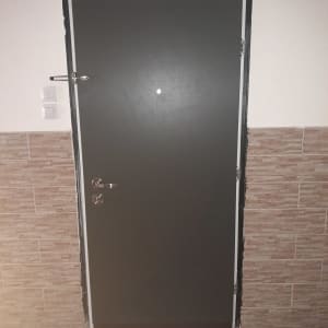 דלת מתכת עם ידית ומנעול על קיר אריחים