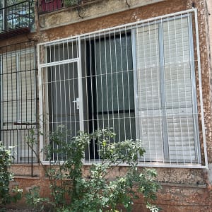 חלון עם סורגים ומסגרת מתכת לבנה