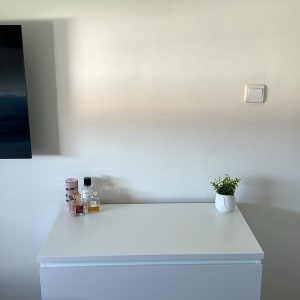 שידה לבנה עם בקבוקי בושם וצמח קטן