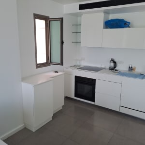 מטבח מודרני עם ארונות לבנים ותנור