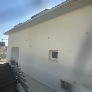 קיר חיצוני של בניין עם חלון קטן ומעקה