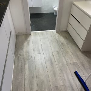 רצפת פרקט עץ בהירה עם מטאטא כחול