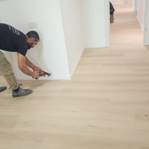 עובד מתקין פרקט בחדר עם רצפת עץ
