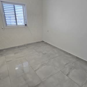 חדר ריק עם רצפת אריחים ודלי ירוק בפינה