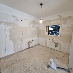 חדר ריק עם קירות מטויחים ורצפת אריחים