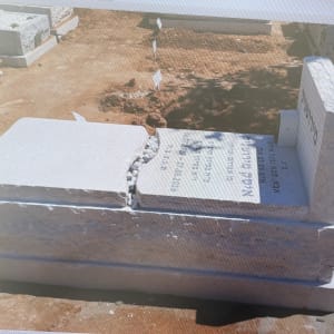 מצבה שבורה בבית קברות עם כיתוב באנגלית