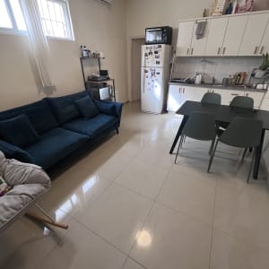 מטבח עם רצפה נקייה ומבריקה, כיור עם כלים, מוצרי ניקוי על הארון