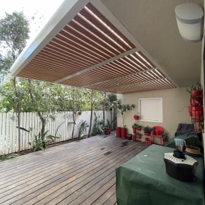 פרגולה מאלומיניום עם קורות עץ בחצר