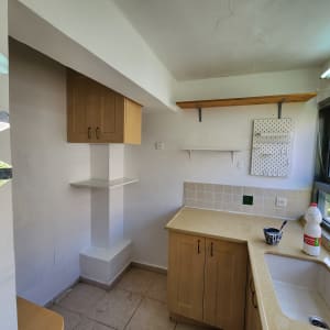 מטבח קטן עם ארונות עץ, כיור ומשטח עבודה