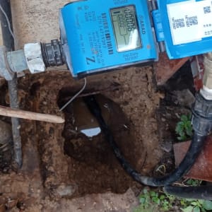 מונה מים כחול מחובר לצינור באדמה