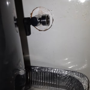 ברז מתכת מותקן בקיר עם מגש מתחתיו