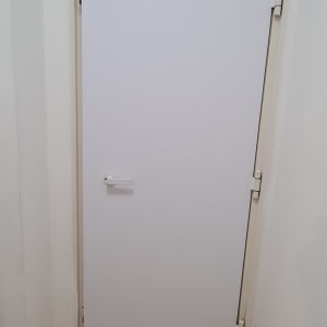 דלת לבנה עם ידית פשוטה וצירים גלויים