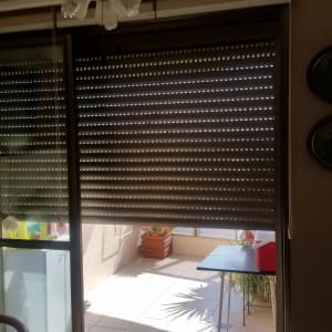 תריסי אלומיניום סגורים על חלון זכוכית גדול