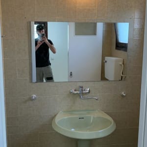 מראה מלבנית תלויה על קיר חדר אמבטיה