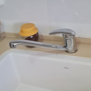 ברז מטבח כסוף מעל כיור לבן עם מגב כתום