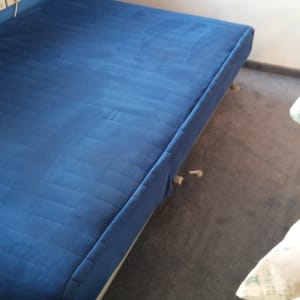 מזרן כחול על מיטה בחדר עם שטיח אפור