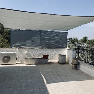 מרפסת עם גדר מתכת ומסגרת צל