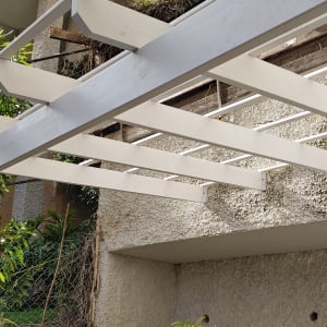 פרגולה מעץ לבן מחוברת לקיר בטון