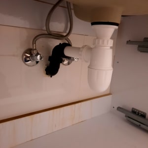 צנרת מתחת לכיור עם ברזים וצינורות